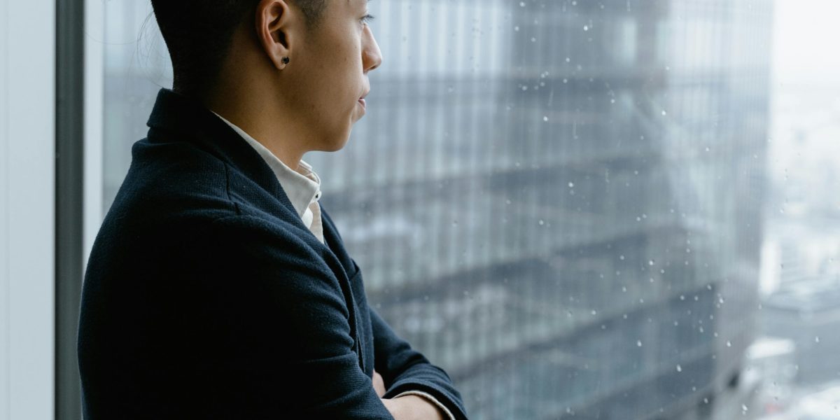 A person looks thoughtfully out a window, contemplating significant life decisions and career paths.