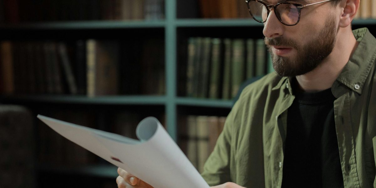 A focused individual engaged in studying within a quiet, organized library or home office environment.