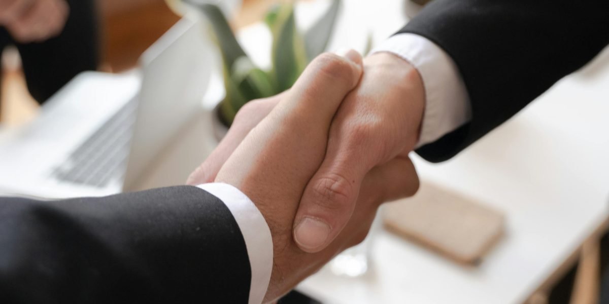 A person shaking hands in a professional setting, symbolizing career success and networking after earning a degree.